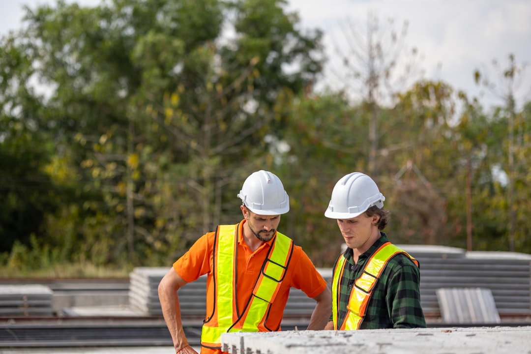 Engineers inspecting plans on a construction site — representing the on-site accreditation visit and evidence review