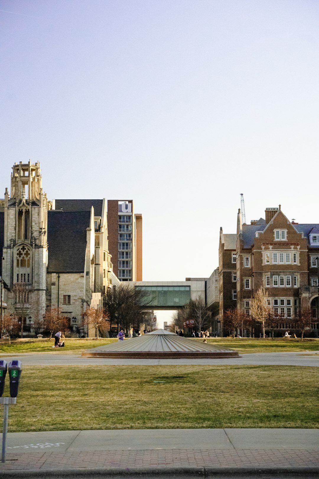 Students sitting on university campus green with engineering buildings in background
