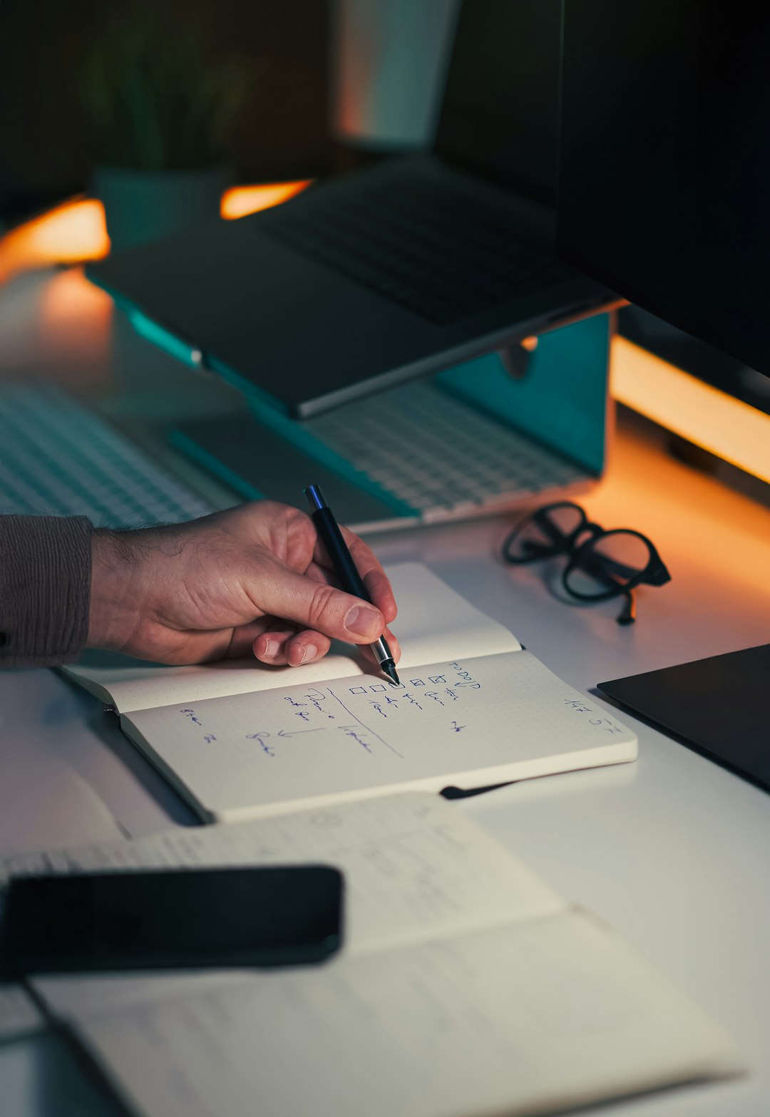 A hand checking off items in a notebook during an annual evidence review