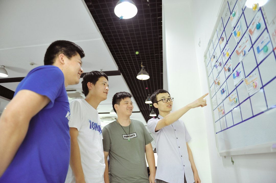 Four faculty members gathered around a whiteboard mapping out an accreditation plan