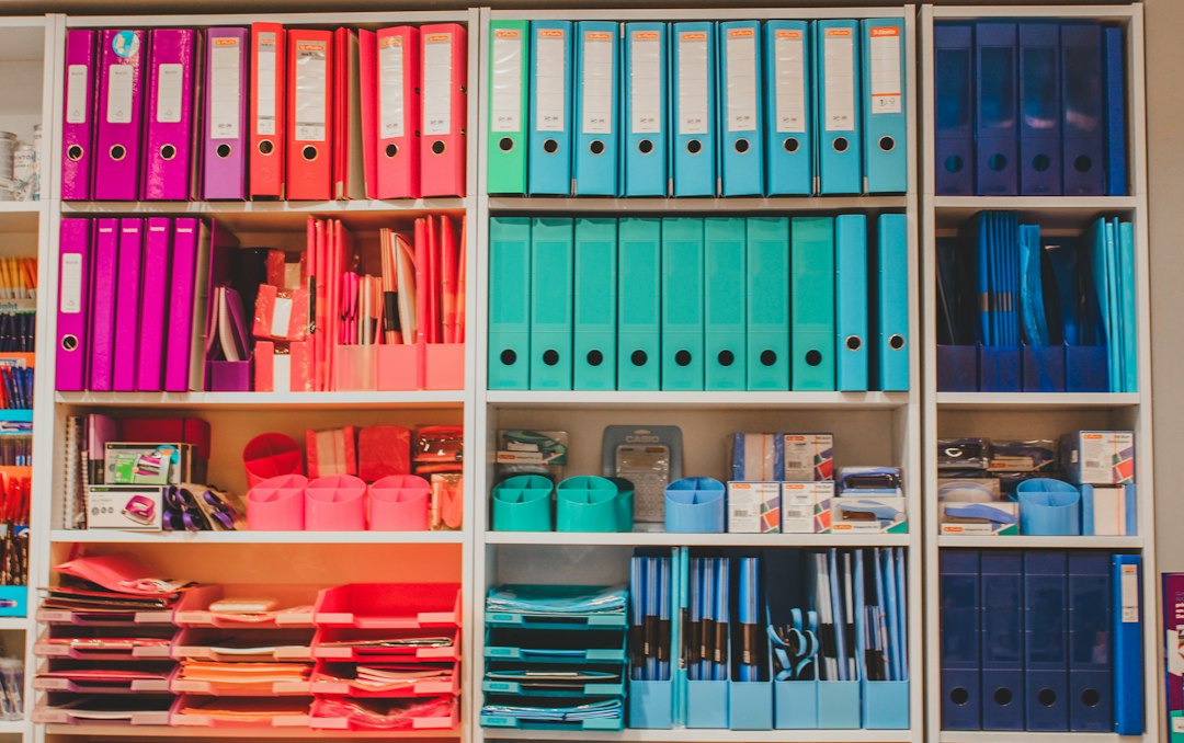 Bookshelf of binders color-coded and organized by category