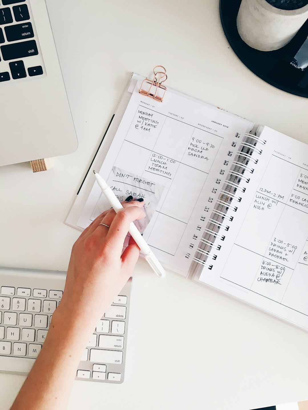 Coordinator checking off items in an open planner beside a laptop