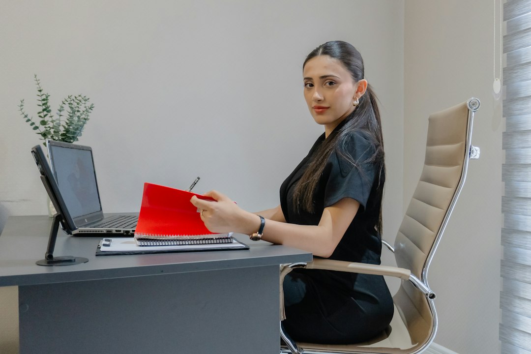 A professional organizing a red folder of accreditation evidence at her desk