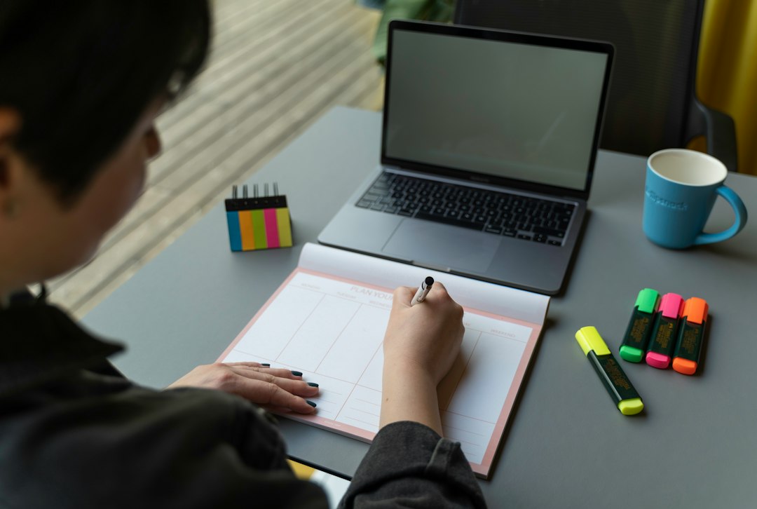 A person writing in a planner at a desk with sticky notes and a laptop, illustrating the evidence-first method of building the narrative from organized materials