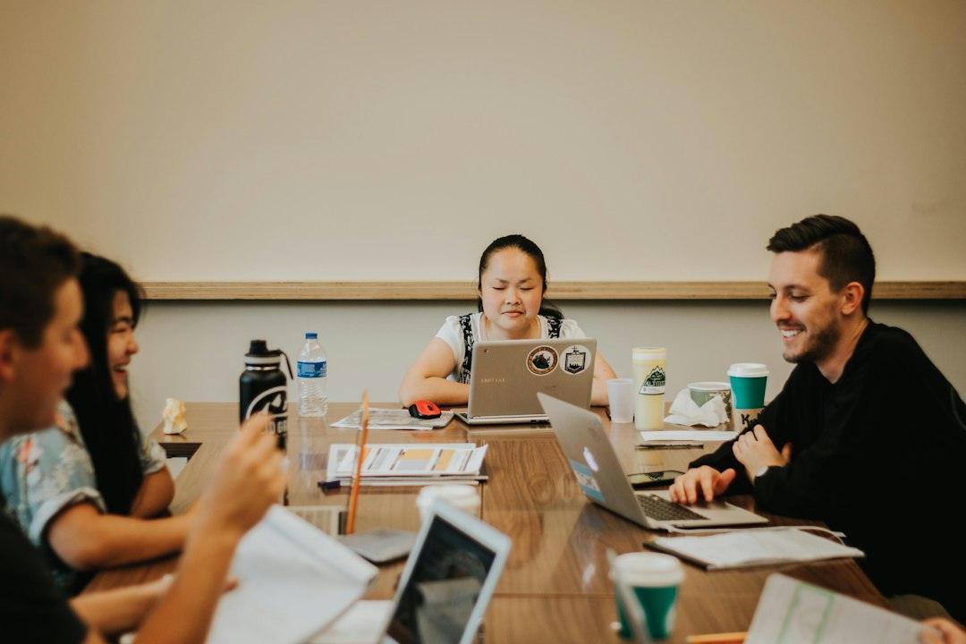 Upper-year students meeting with the visiting team around a table of laptops and notes