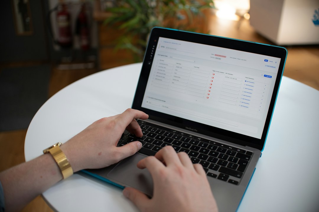 Hands typing on a laptop showing a live readiness dashboard, monitoring accreditation data in real time