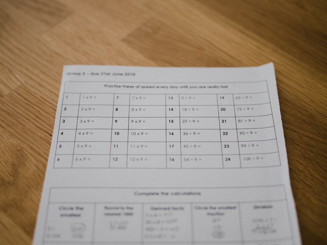 A printed worksheet with a grid of rows and columns on a wooden table, representing the paper tracking forms that often trap course-file evidence
