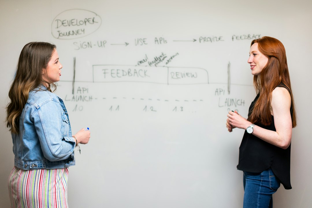 Two engineers discussing curriculum mapping in front of a whiteboard