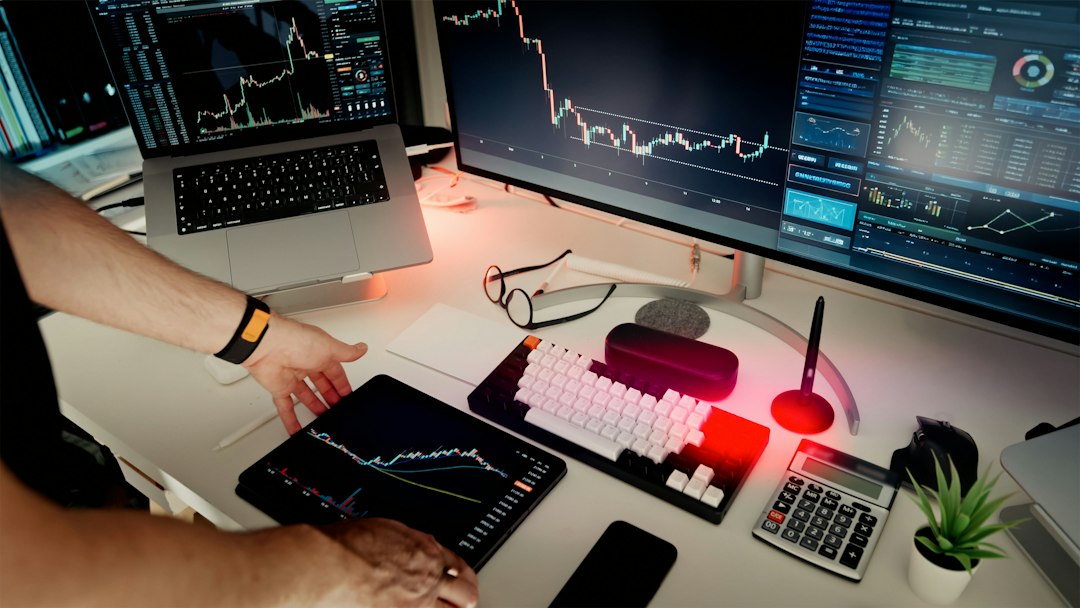 A person at a desk with multiple monitors showing data — the AI feature arms race in accreditation tools
