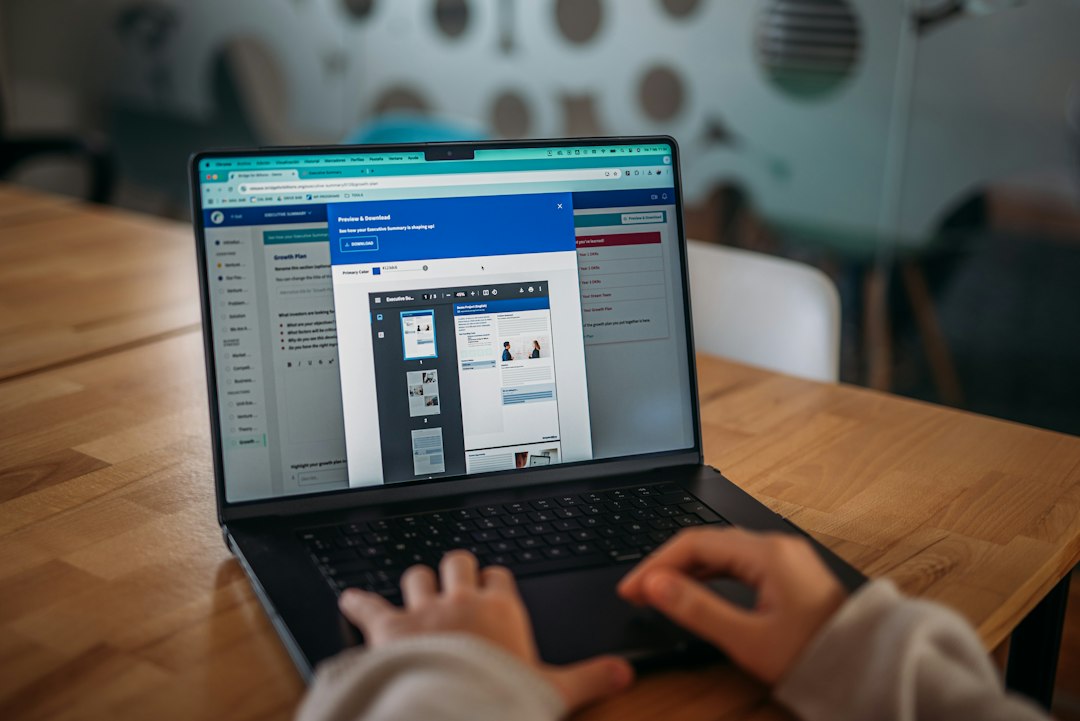 Coordinator working through a digital submission portal on a laptop at a wooden desk