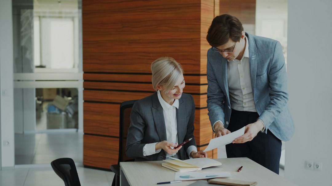 Two colleagues reviewing documents together at an office desk