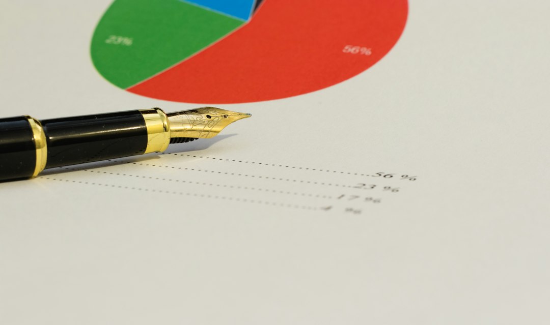 A black fountain pen on a printed pie chart with handwritten calculations beside it